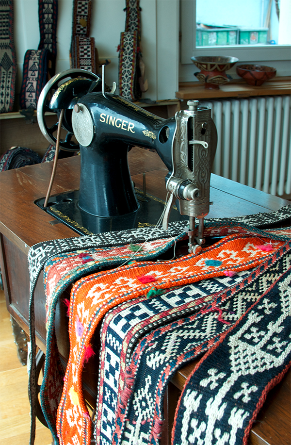 antike Singer Nähmaschine mit Holztisch. Orientale Taschengurte Webbänder in Orange, schwarz-weiss und rot.